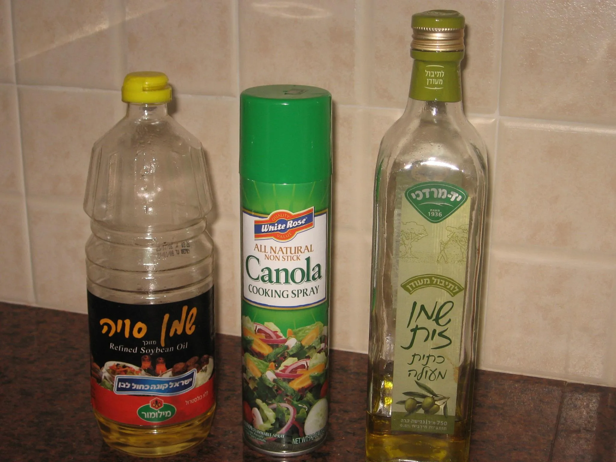 Assorted cooking oil bottles and Indian ingredients on a warm wooden table